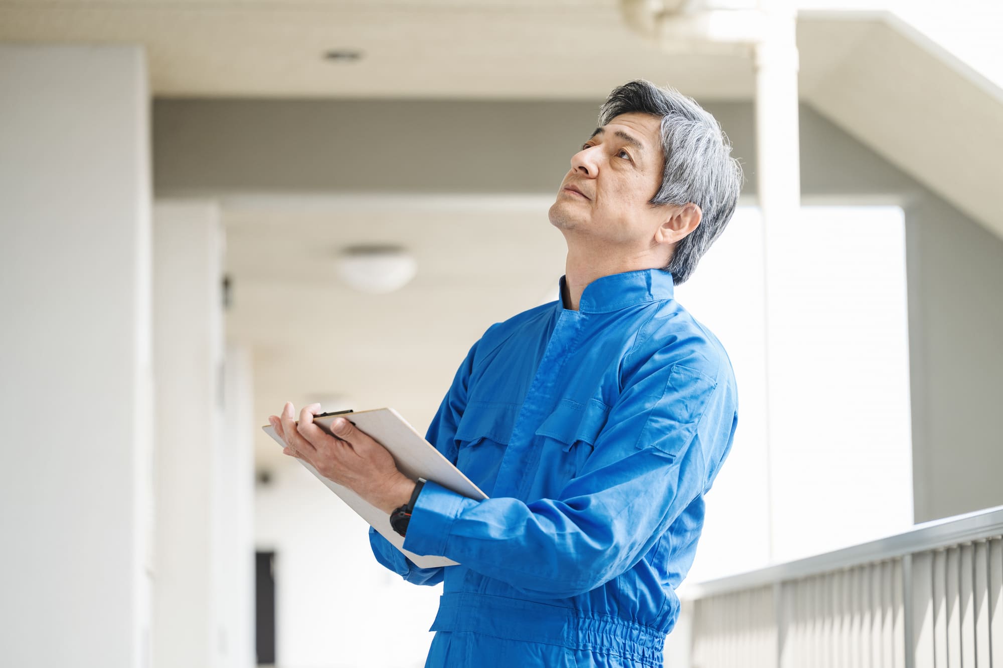マンションの外観を目視確認で定期点検をしている作業員
